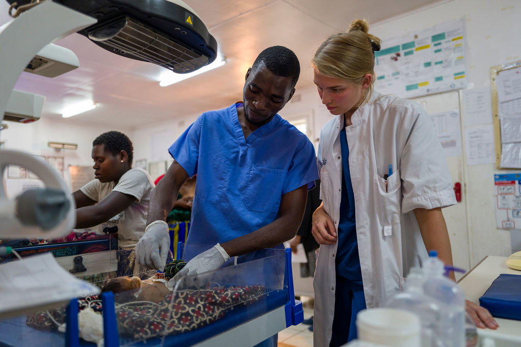 A surgical team in scrubs and masks works together over a patient in an operating room at an MBF partner hospital.